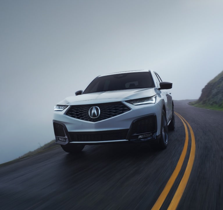 2026 Acura MDX Advance Package in Platinum White Pearl driving on road 2026 Acura MDX Advance Package in Platinum White Pearl driving on road